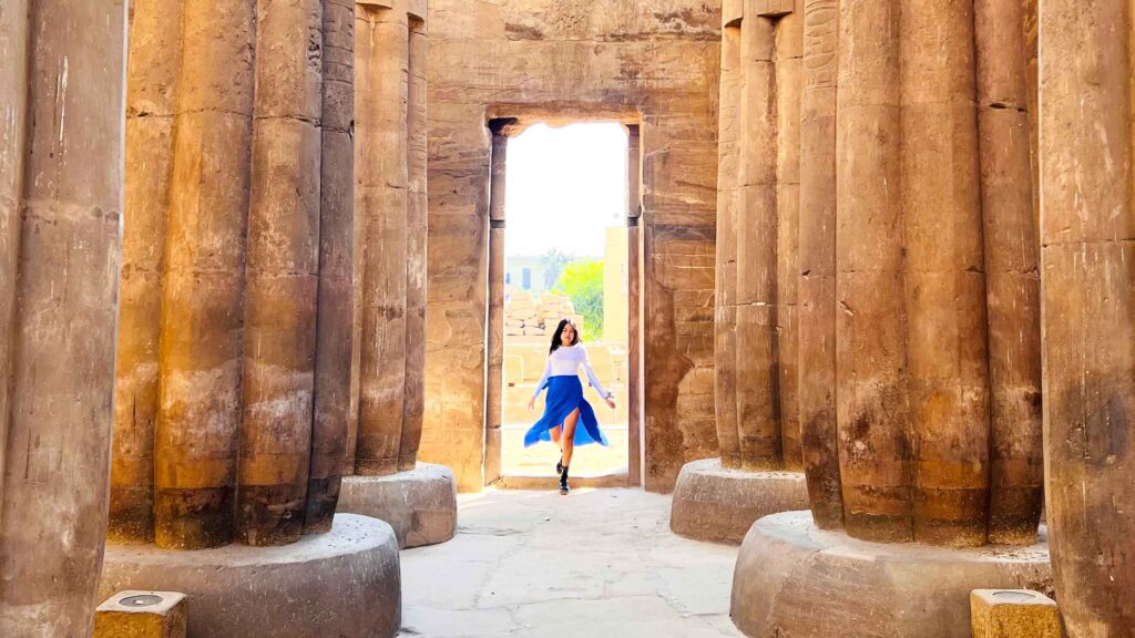 Aurora walking between the columns at Karnak Temple, Luxor